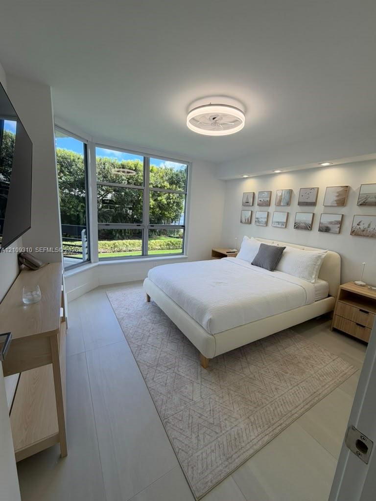 Large bay windows, recessed ceiling lighting, circular modern ceiling fixture, and light-toned flooring