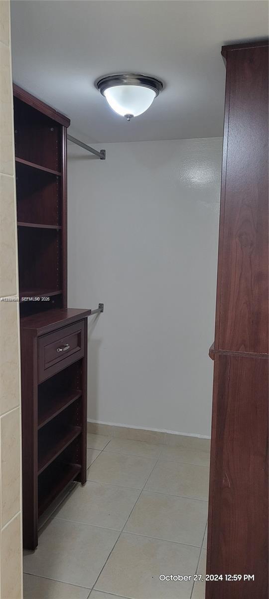 Built-in wood-finish cabinetry with shelving and a drawer, light-toned tile flooring, and a dome ceiling light fixture