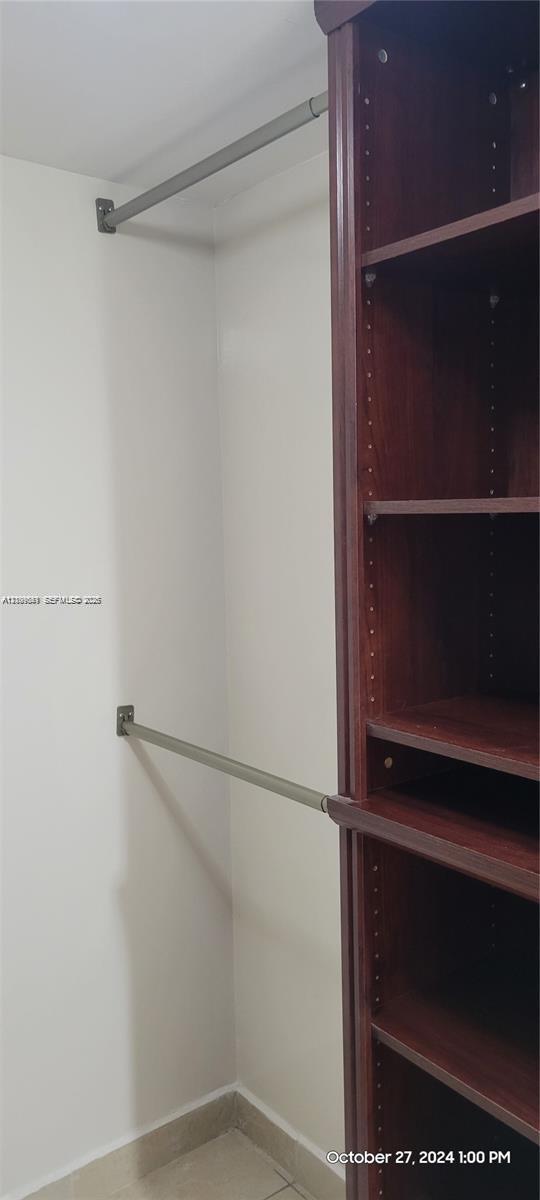 Storage space featuring wood-finish built-in shelving and dual-level metal hanging rods