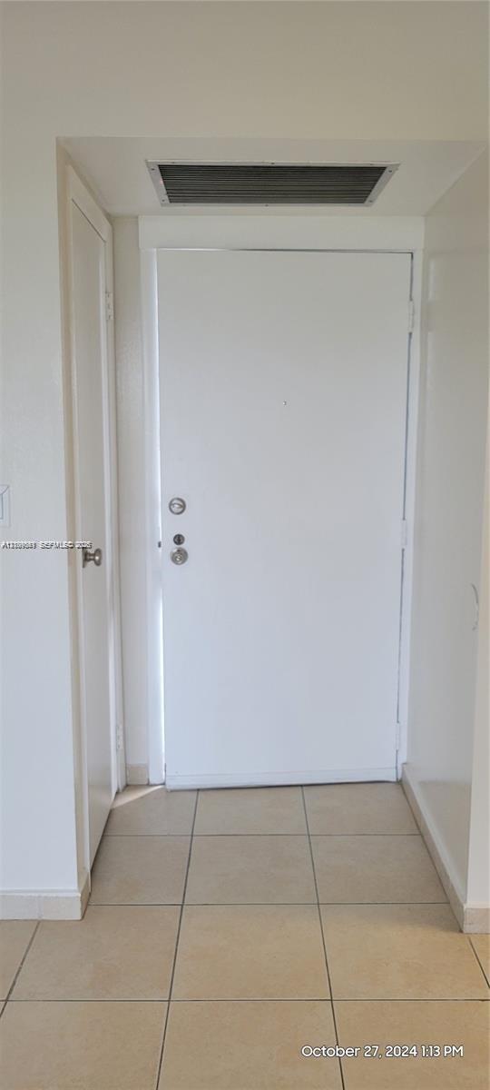 Entryway featuring a solid-core door with metallic deadbolt hardware and square ceramic tile flooring