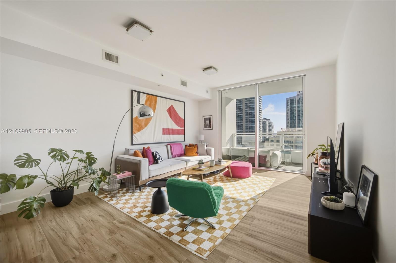 Living area featuring wood-finish flooring, recessed ceiling lighting, and large sliding glass doors providing access to a private balcony