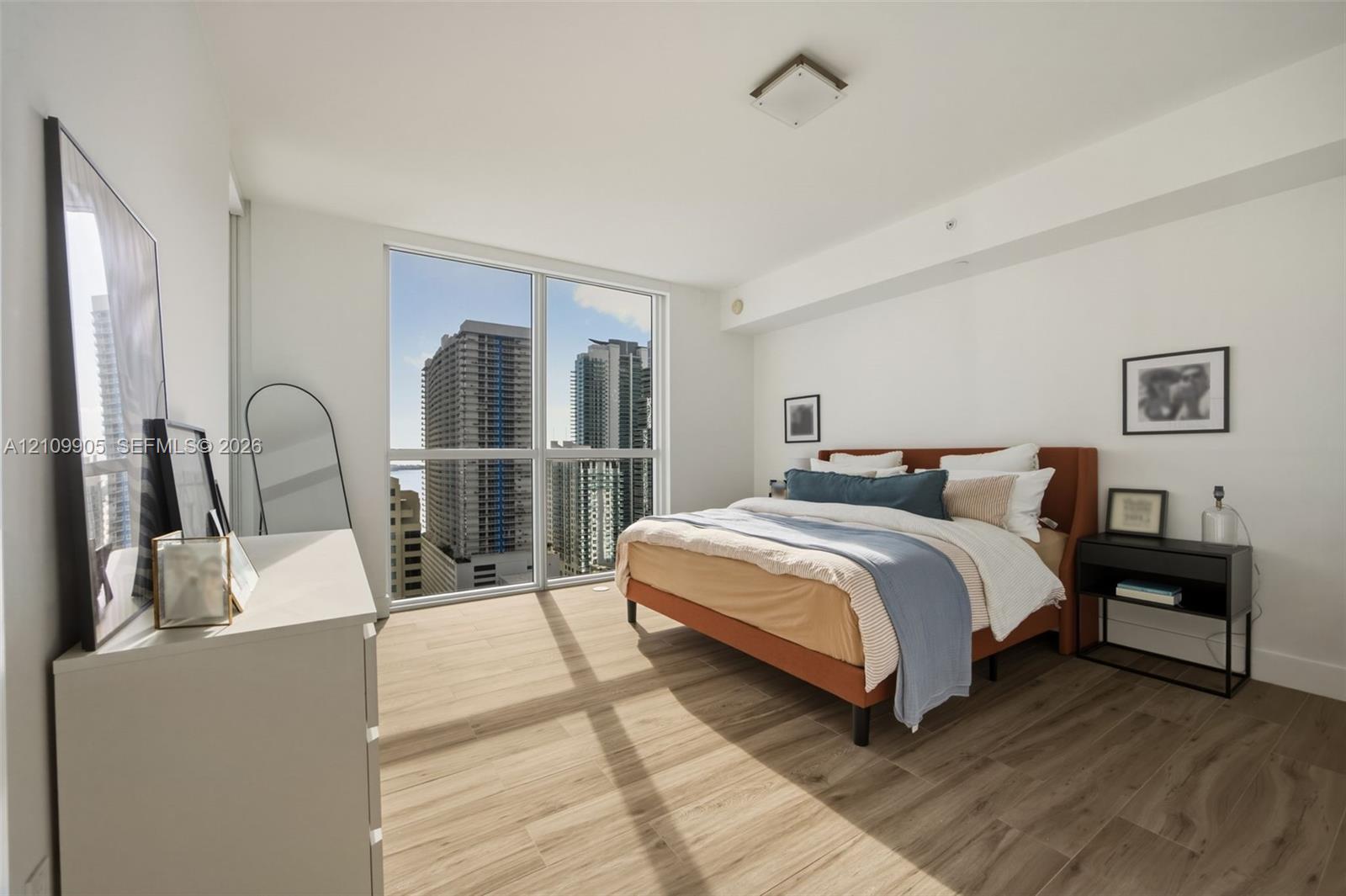 Floor-to-ceiling windows featuring urban scenery, wood-finish flooring, and flush-mount ceiling lighting