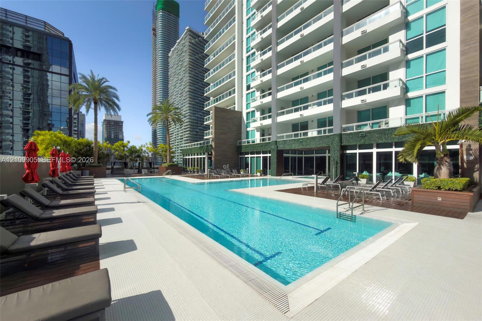 Outdoor swimming pool featuring a lap lane, tiled pool deck, built-in wooden planter boxes, and perimeter hedging