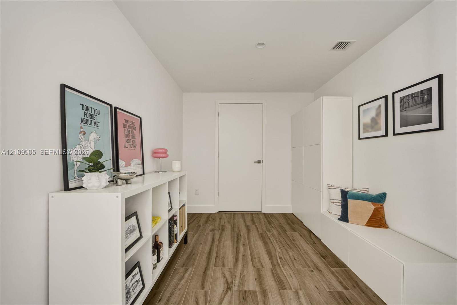 Interior hall featuring wood-finish flooring, white walls, and built-in white cabinetry