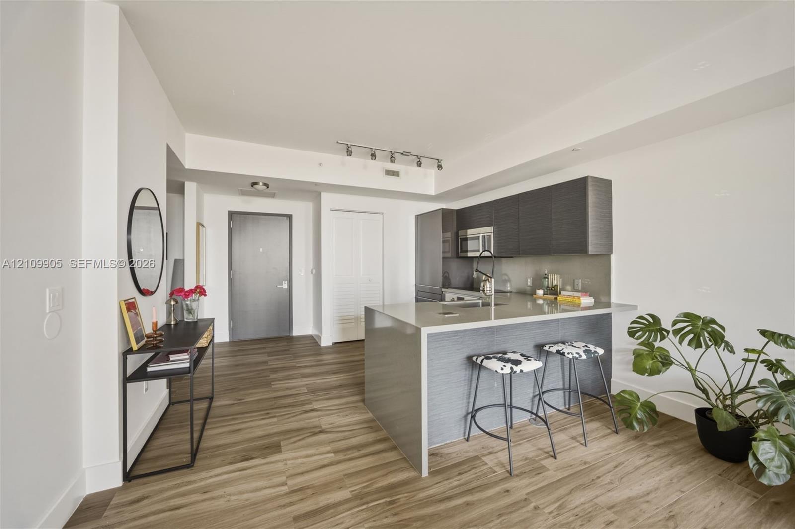 Kitchen area featuring a center island with a stone-finish countertop, dark-toned cabinetry, stainless steel appliances, and wood-finish flooring