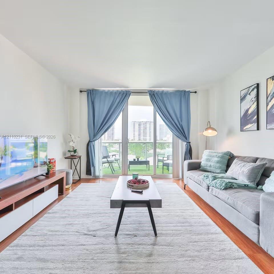 Living area featuring wood-finish flooring, floor-to-ceiling glass sliding doors, and a private balcony