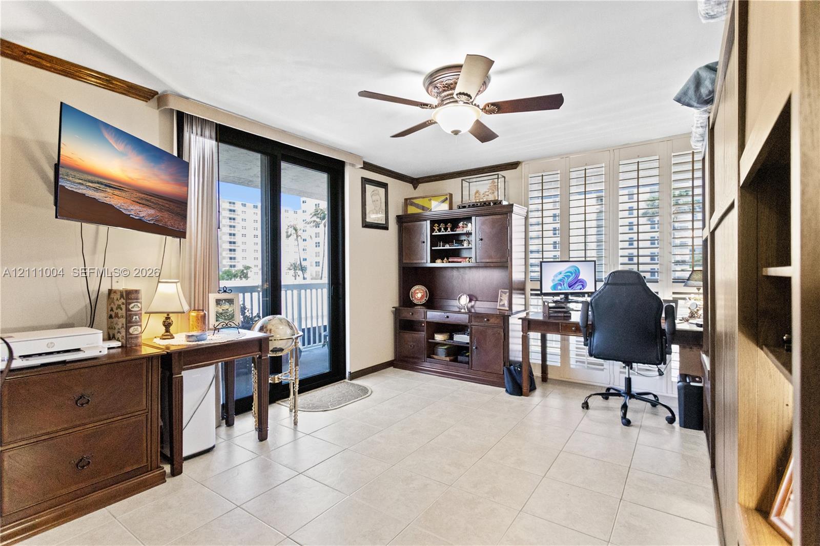 Tile flooring, plantation shutters, built-in wooden cabinetry, ceiling fan, and sliding glass door