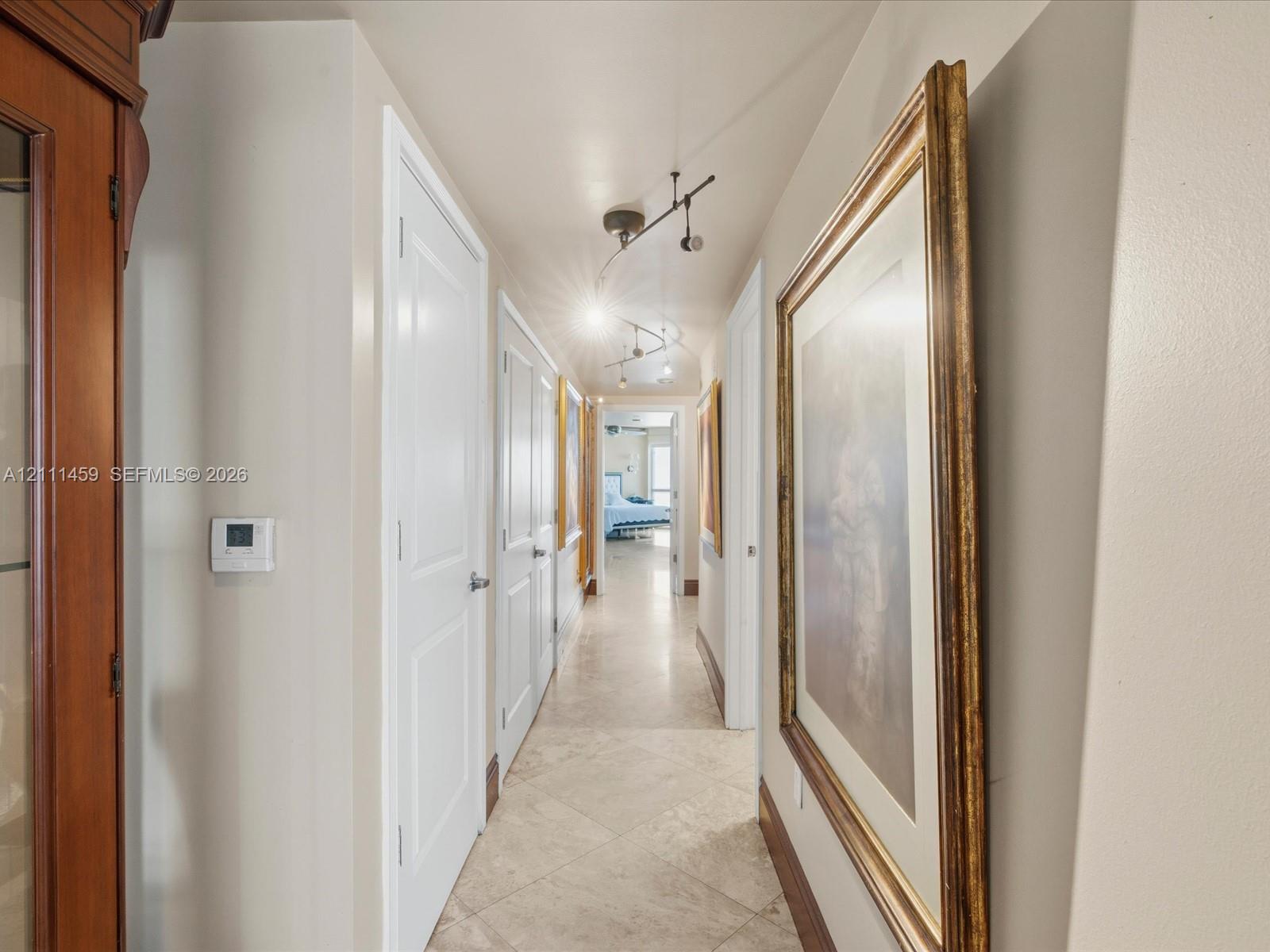 Hallway featuring large-format tile flooring, multi-panel doors, and adjustable track lighting