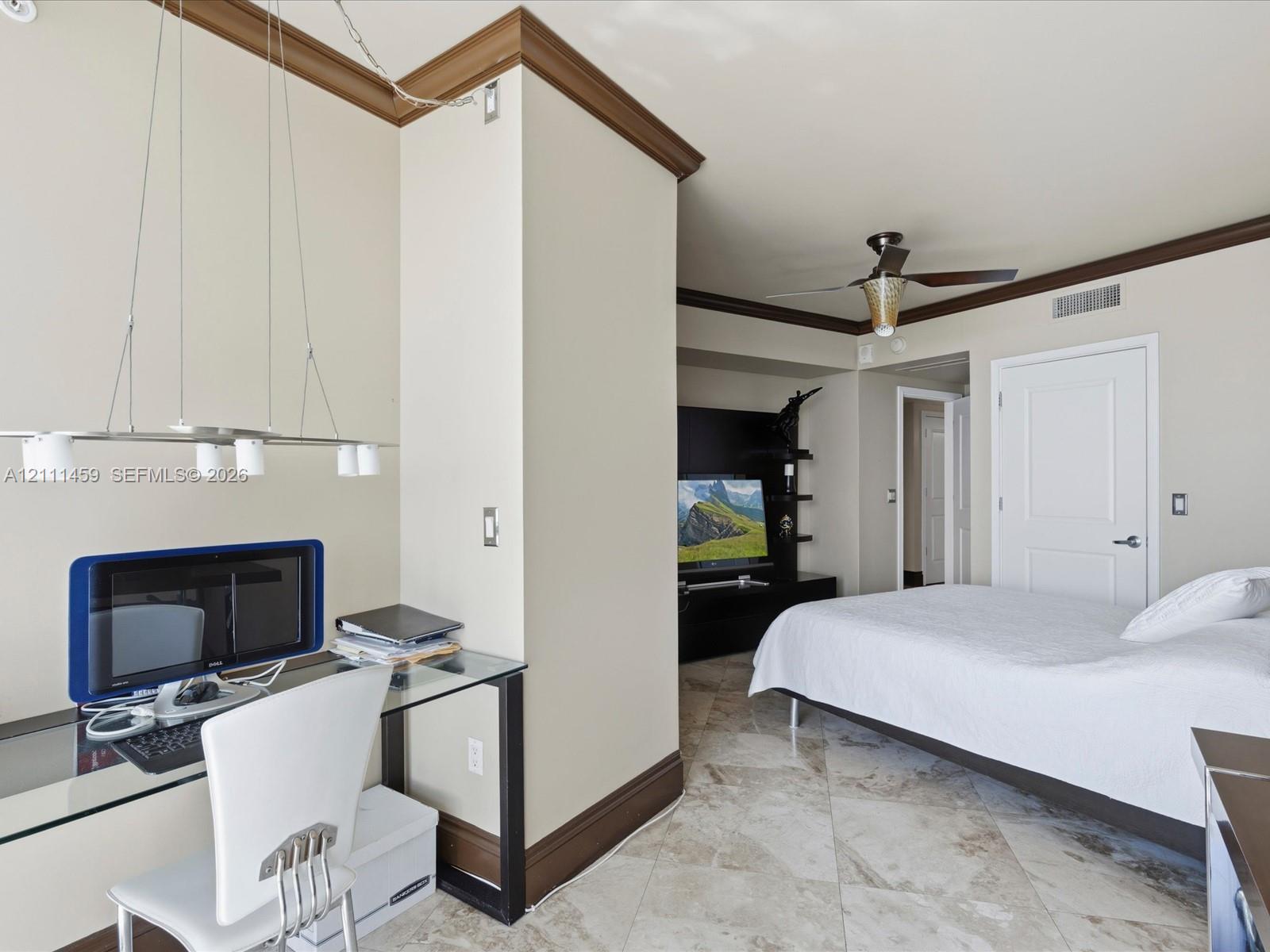 Stone flooring, decorative crown molding, built-in entertainment shelving, and a modern ceiling fan
