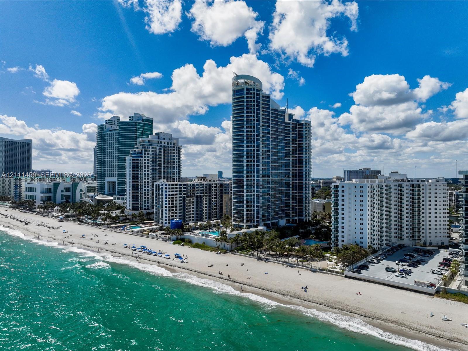 High-rise coastal architecture featuring glass curtain walls and direct access to an expansive sandy beach