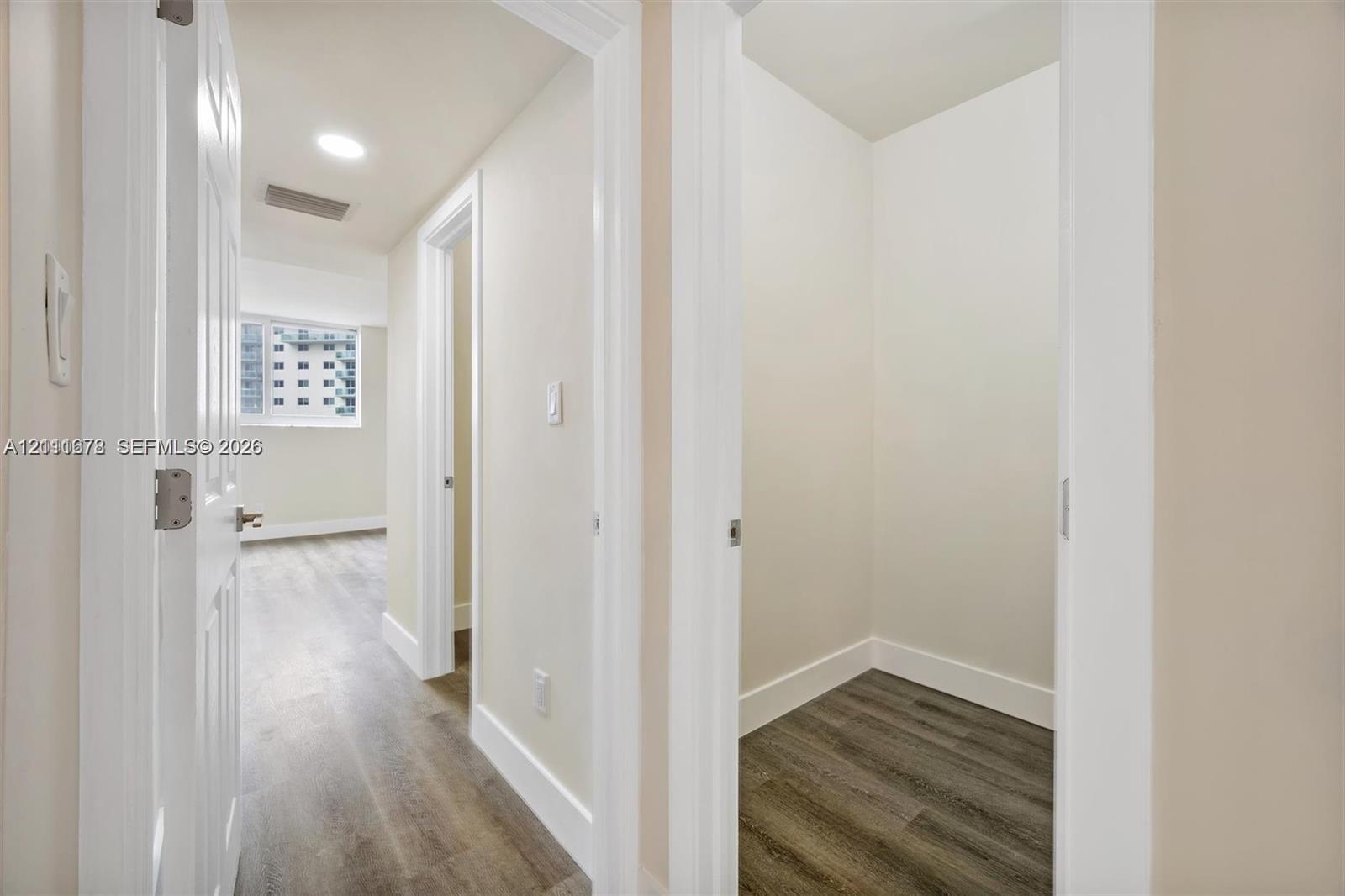 Interior hallway featuring wood-finish flooring, white panel doors, and recessed lighting