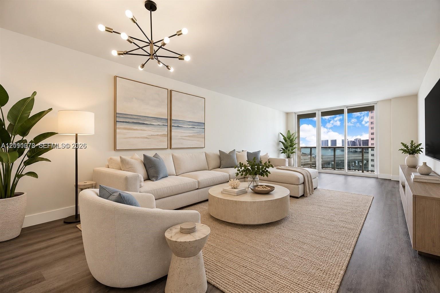 Spacious interior featuring wood-finish flooring, a modern multi-arm chandelier, and floor-to-ceiling glass sliding doors opening to a balcony