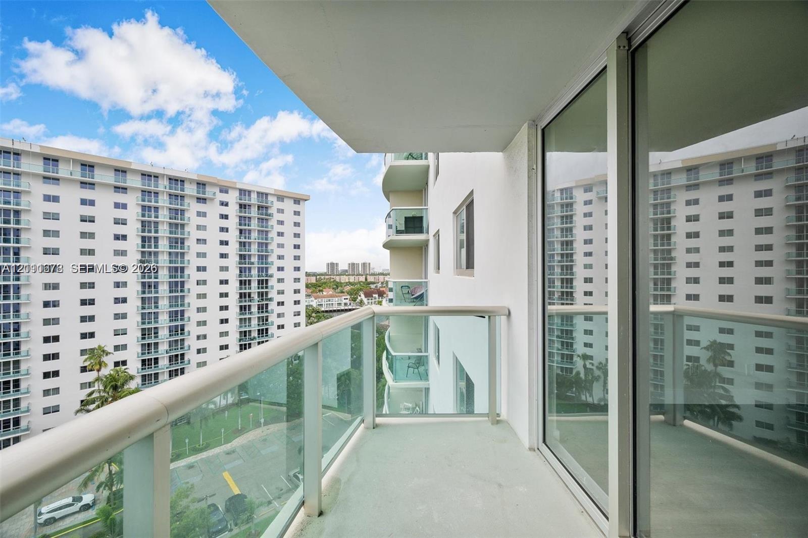 Covered balcony featuring glass pane railings and full-height sliding glass doors