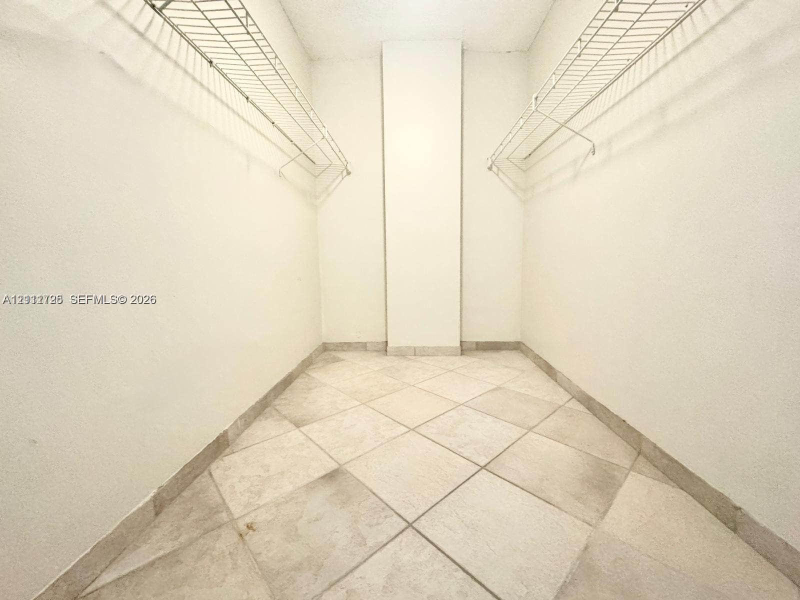 Storage space featuring neutral large-format tile flooring and dual tiered wire shelving systems