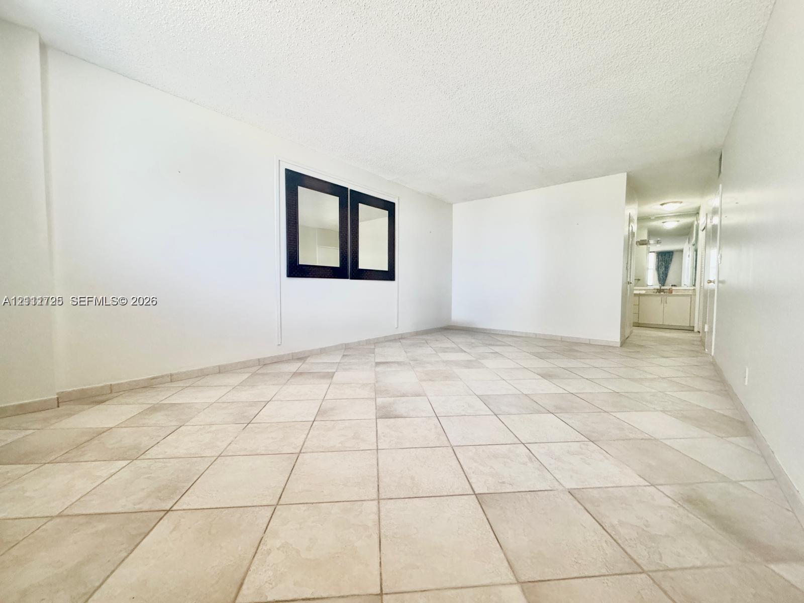 Open-concept living space featuring large-format ceramic tile flooring, neutral walls, and a recessed black-framed wall mirror